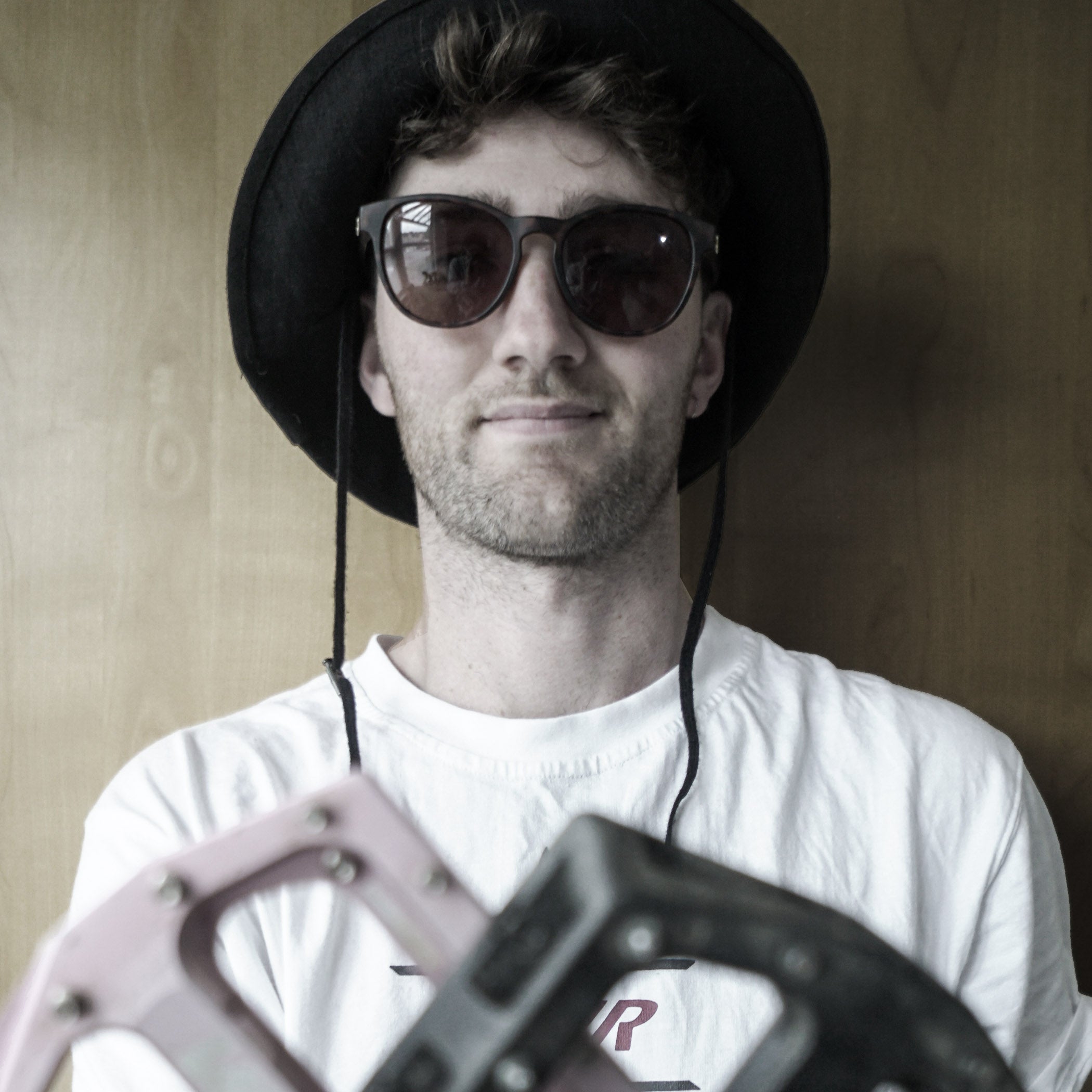 Man wearing sunglasses and a black hat with a blurred object in the foreground