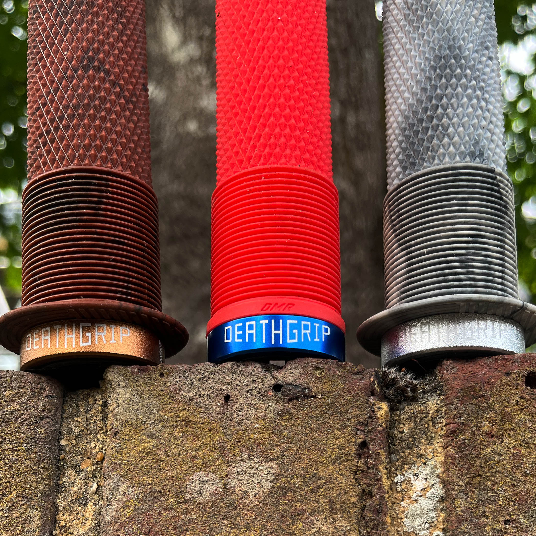 Three handlebar grips in brown, red, and gray on a textured surface with 'Deathgrip' branding.