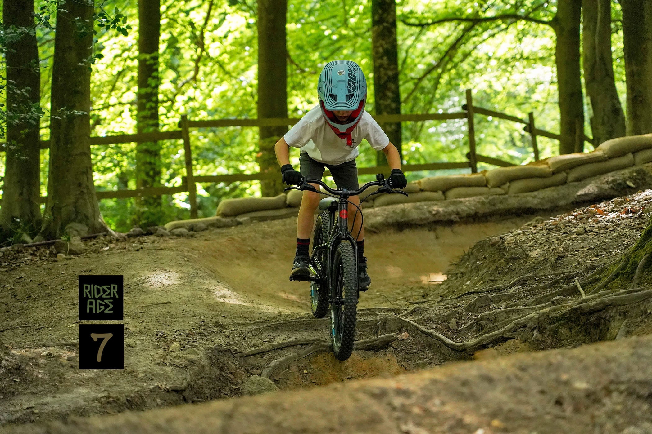 DMR Sidekick Ride off-road kids children child mountain cycling cycle bicycle bike being ridden by a child kid at Rogate Bikepark. The child kid is wearing a blue helmet, white t-shirt, grey shorts and black shoes.