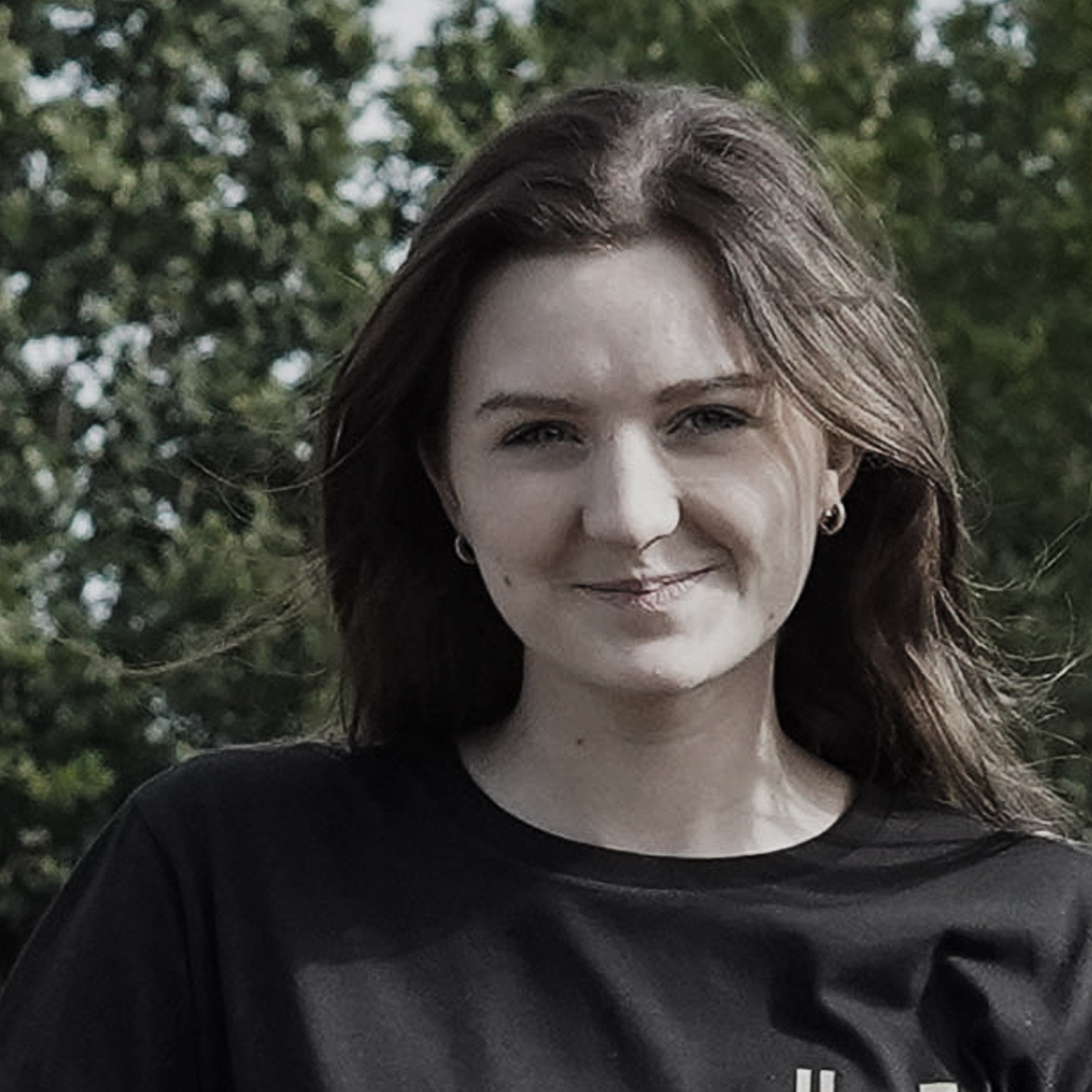 Woman wearing a black shirt with trees in the background
