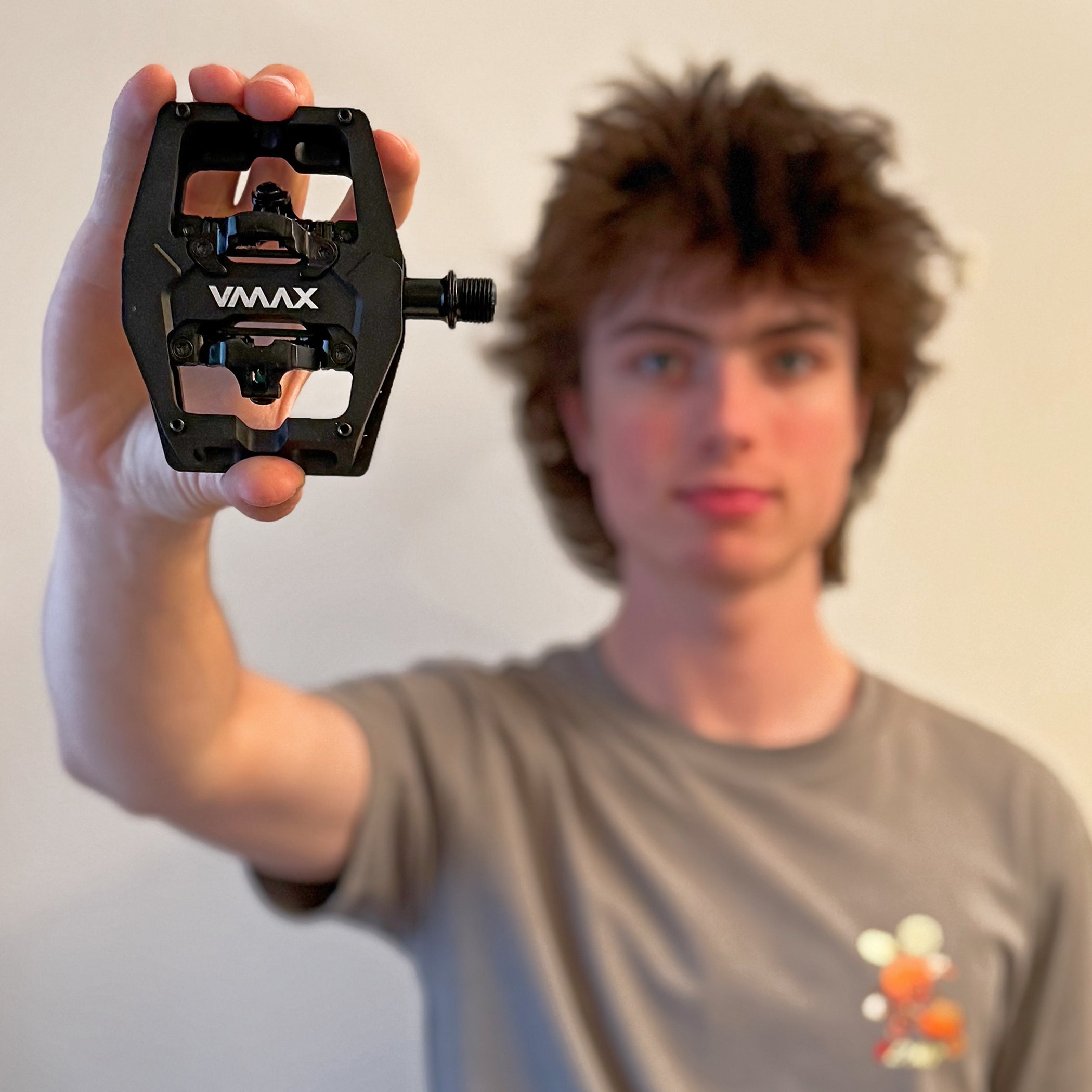 Black DMR VMAX Pedal being held by a human being that goes by the name James Weeks. He has a grey shirt on and the background is white.
