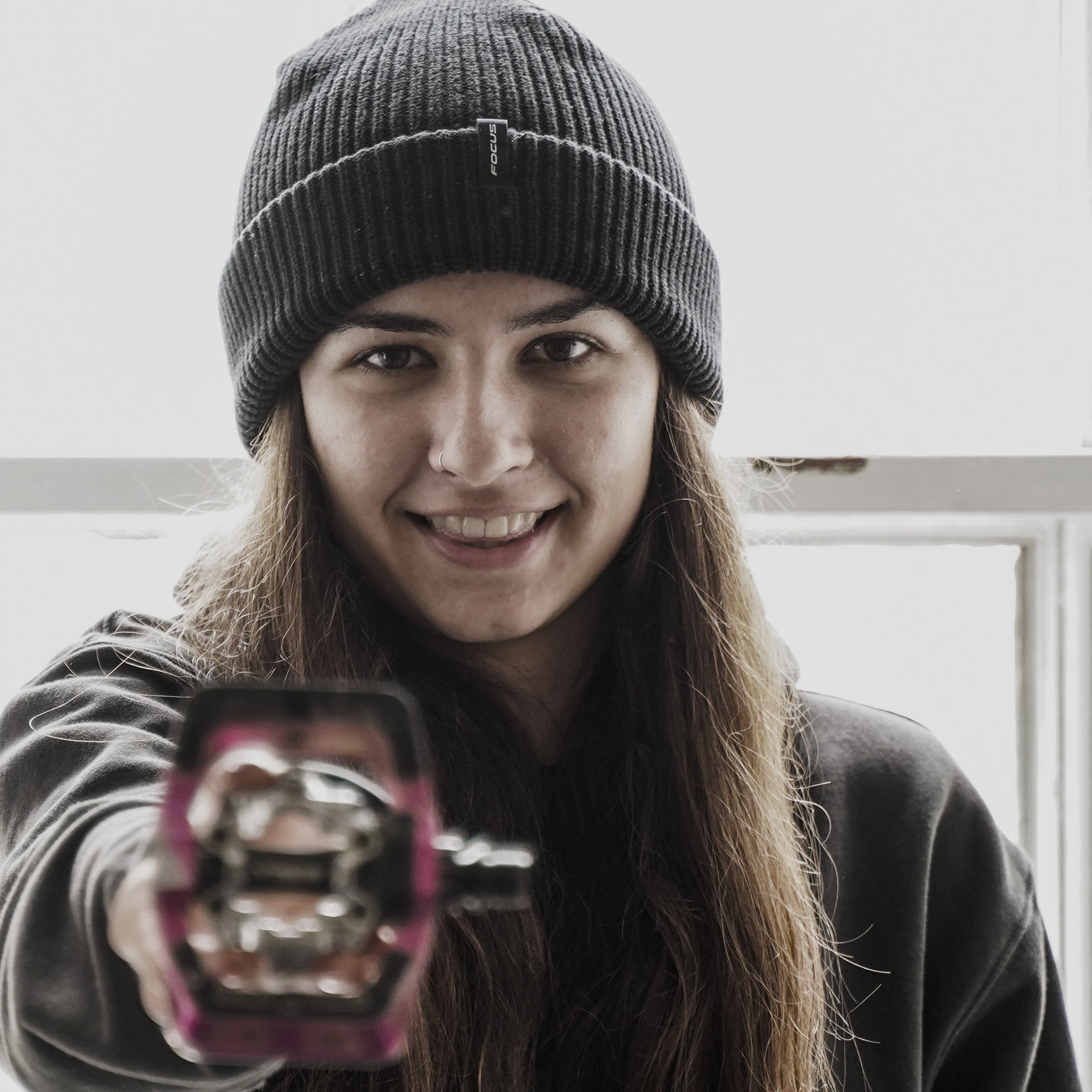 Person wearing a beanie holding a reflective object with a blurred background