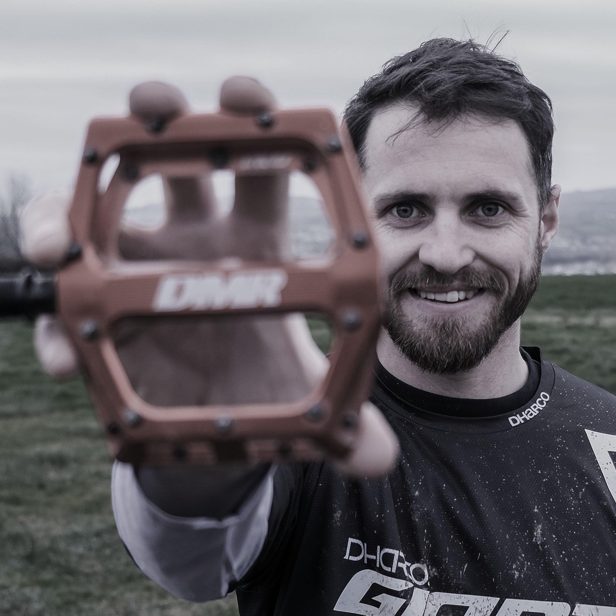 Man holding a brown bicycle pedal with a blurred background