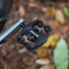 Black DMR VMAX off-road mountain cycle cycling pedal pedalling product, placed upon a autumnal background, with leaves and other fauna.
