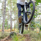 bronze DMR VMAX off-road mountain cycle cycling pedal pedalling product, under the foot of a rider, with a blurry green background.