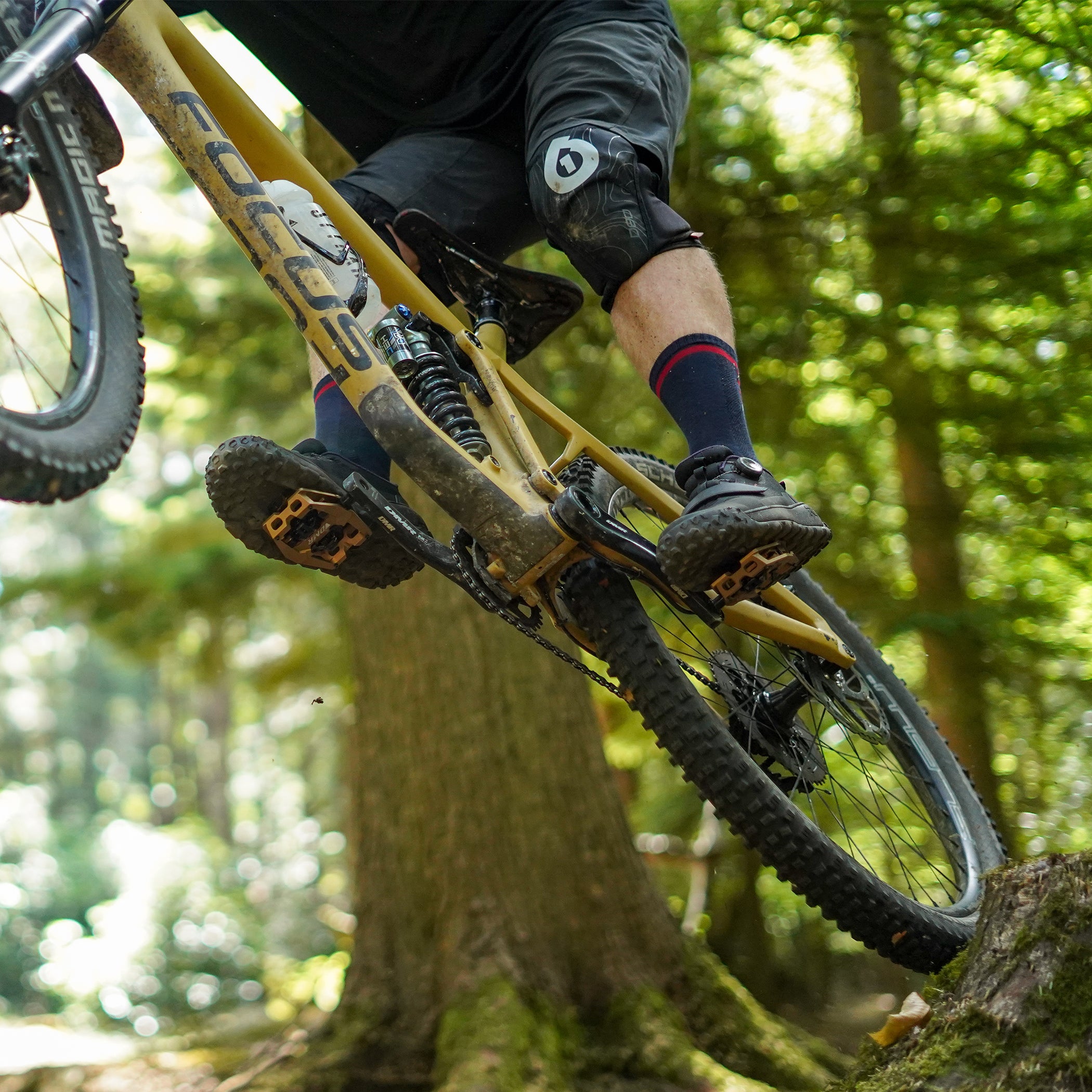 Light Bronze DMR VMAX clipless clip-in clip clipped SPD off-road mountain cycling bicycle bike pedalling pedal product, being used on an off-road mountain cycling cycle bicycle bike, pictured riding off the stump of a tree.
