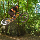 Light Bronze DMR VMAX clipless clip-in clip clipped SPD off-road mountain cycling bicycle bike pedalling pedal product, being used on an off-road mountain cycling cycle bicycle bike, pictured riding off a jump in the woods.