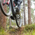 Black DMR VMAX off-road mountain cycle cycling pedal pedalling product, under the foot of a rider, with a blurry green background.