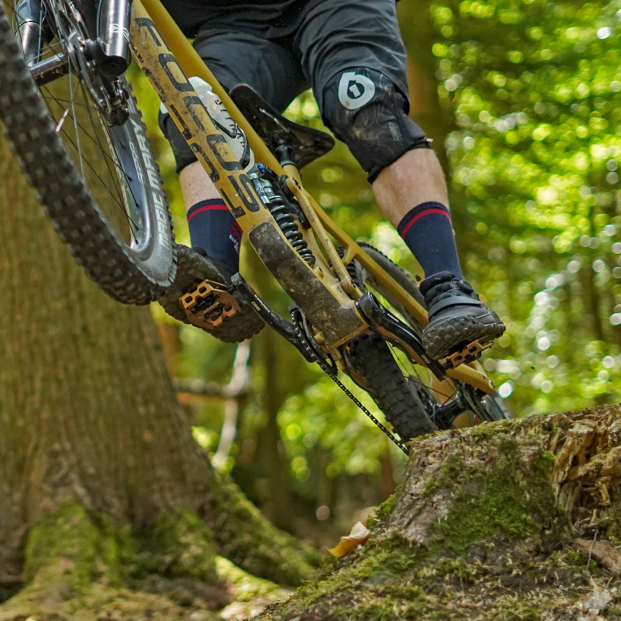 DMR VMAX off-road mountain cycle cycling bike bicycle pedal pedalling product, coloured light bronze brown, placed on a log, in front of a leaf-covered background.