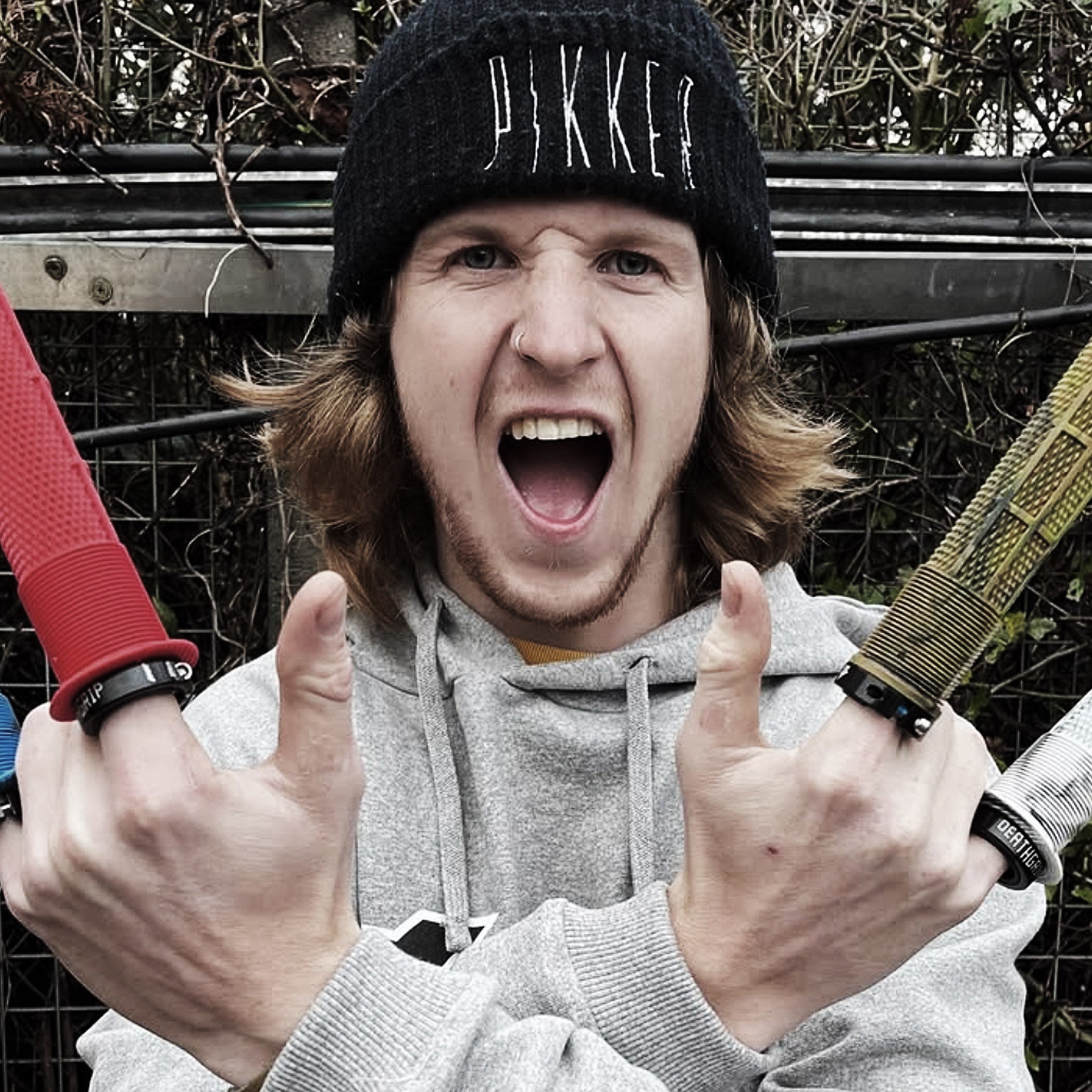 Person wearing a beanie with 'Dikker' branding, holding a tool outdoors.