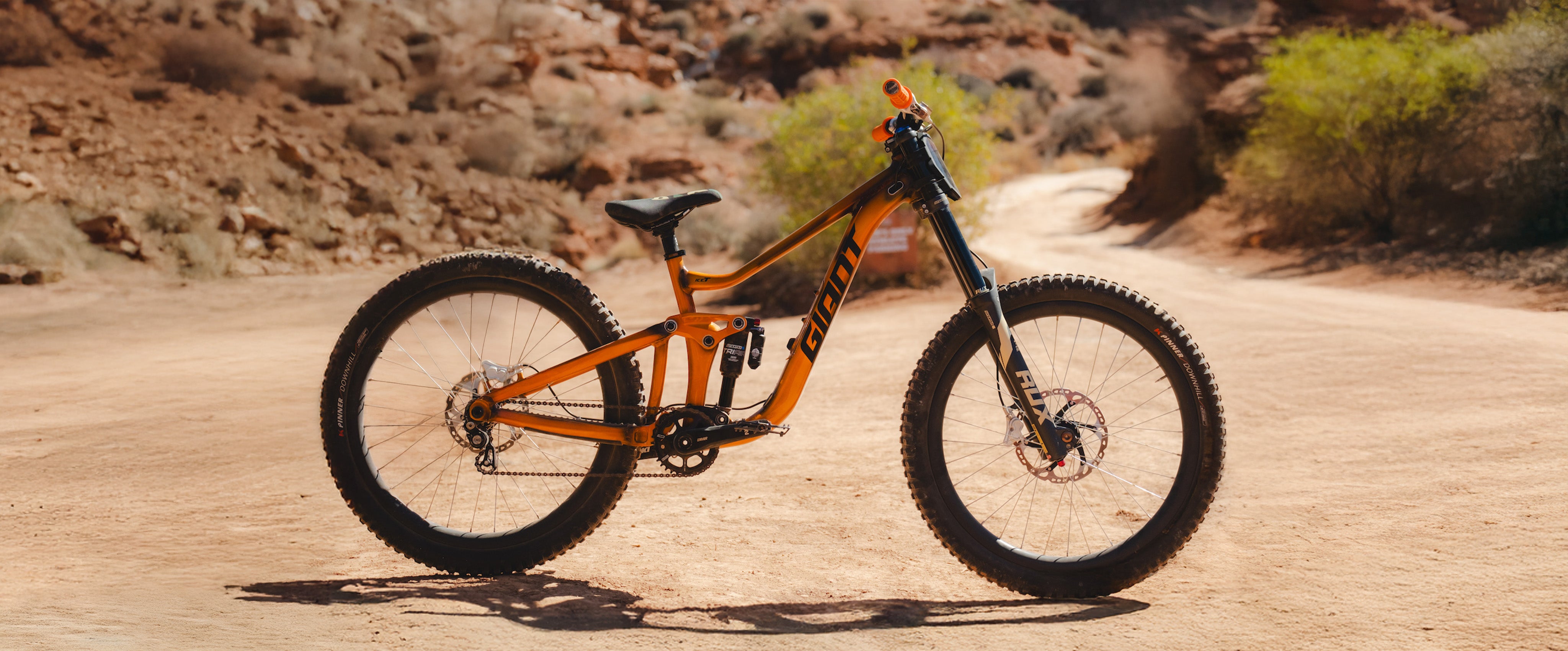 Orange mountain bike on a dirt road with desert landscape
