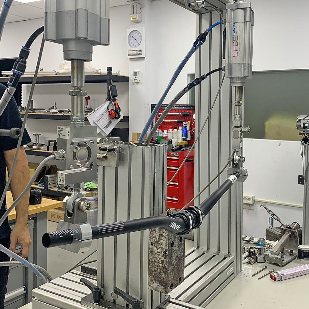 DMR Odub handlebar on a testing machine in a laboratory setting with tools and equipment around.