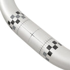 Close-up of a silver ODUB handlebar with black and gray chequered pattern and measurement lines.