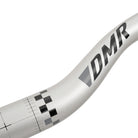 Close-up of a silver ODUB handlebar with the brand name 'DMR' printed in black and gray.