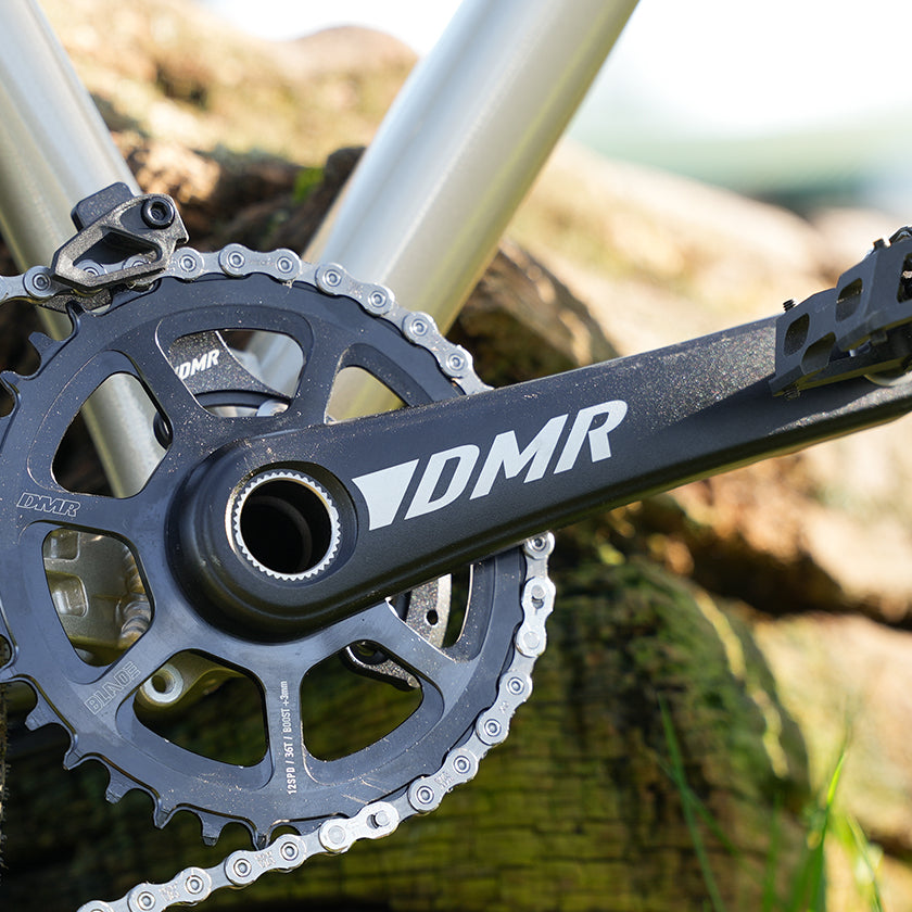 DMR Sect Cranks in Black, fitted to a DMR Rhythm Expert, with wood in the background.