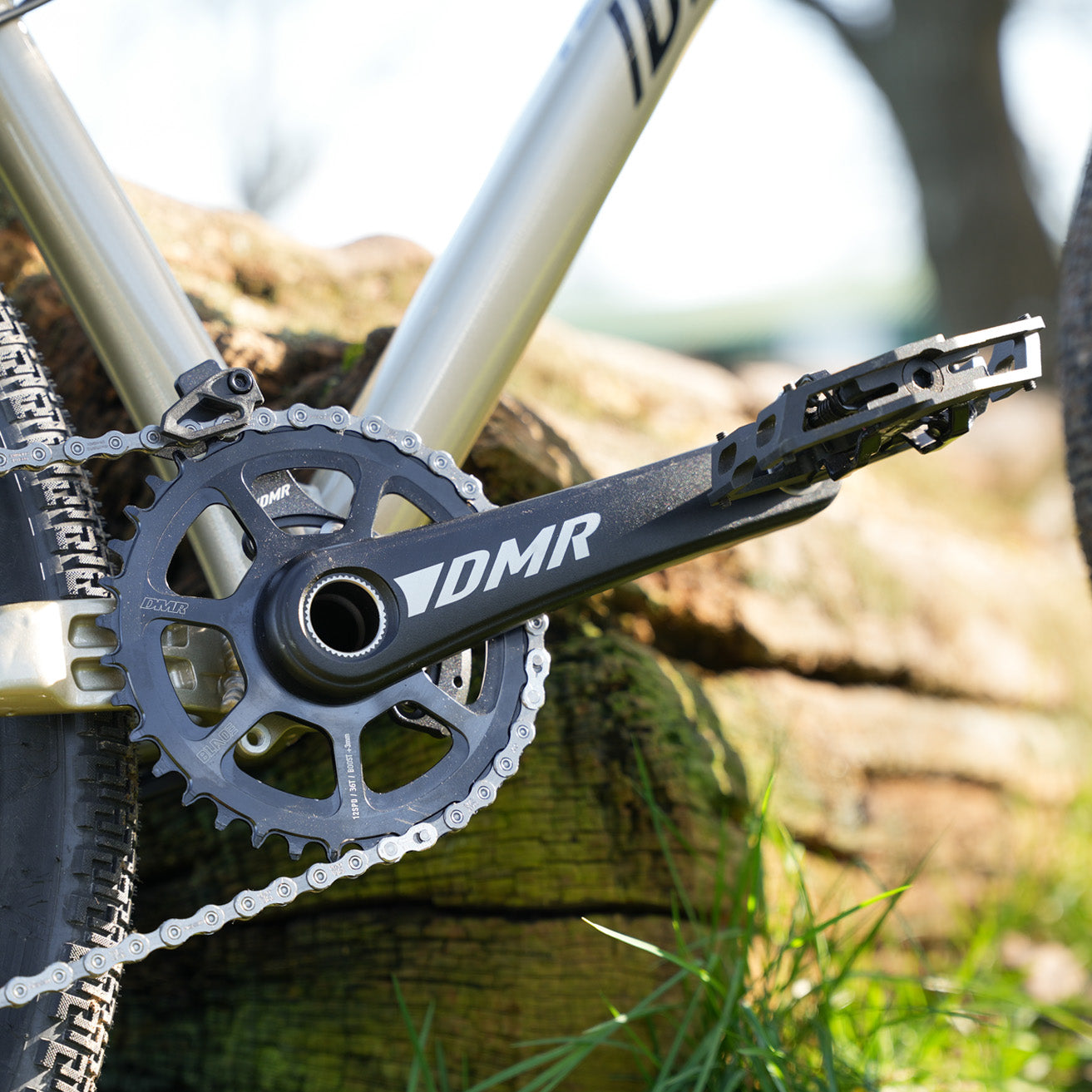 DMR Sect Cranks in Black, fitted to a DMR Rhythm Expert, with wood in the background.