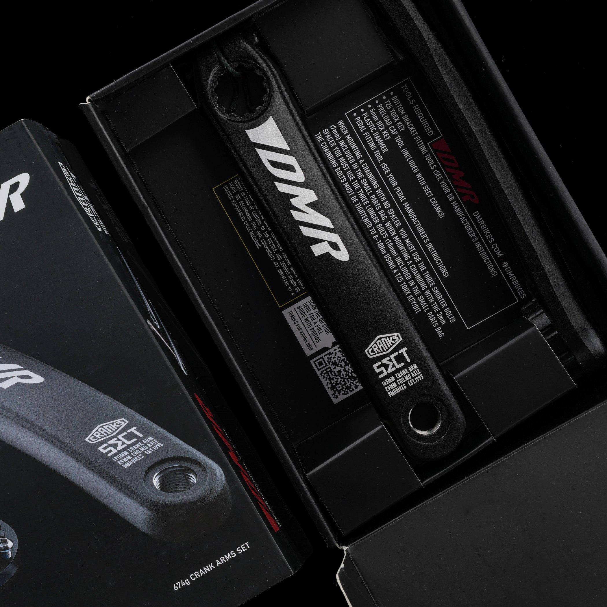 Close-up of black MTB crank with 'DMR' branding on a dark background