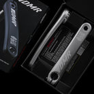 Open box containing DMR bicycle crank arms with packaging.