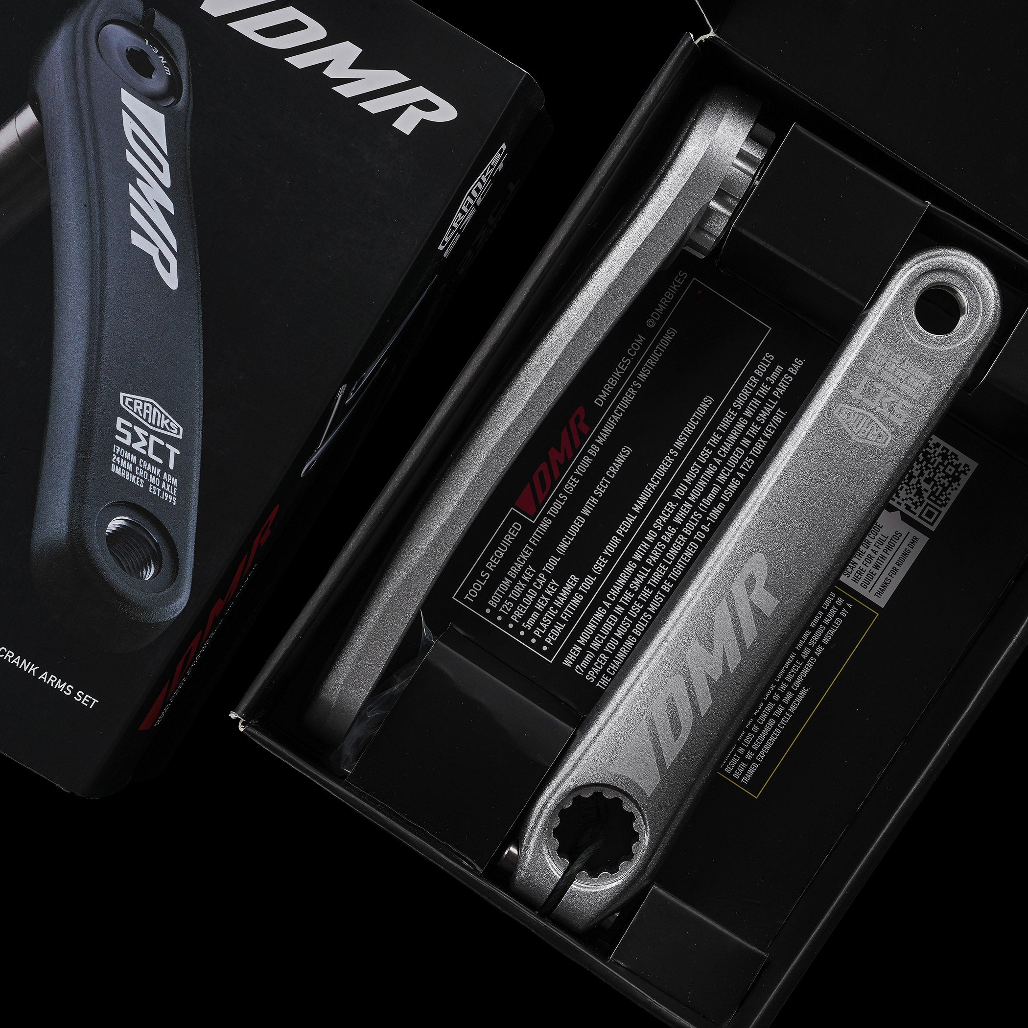 Open box containing DMR bicycle crank arms with packaging.