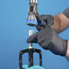 silver dmr bikes bicycles vmax vault mag magnesium midi v12 v11 flat4 flat 4 four versa clip clipless pedals pedal service servicing tool in use with a hammer on a blue background