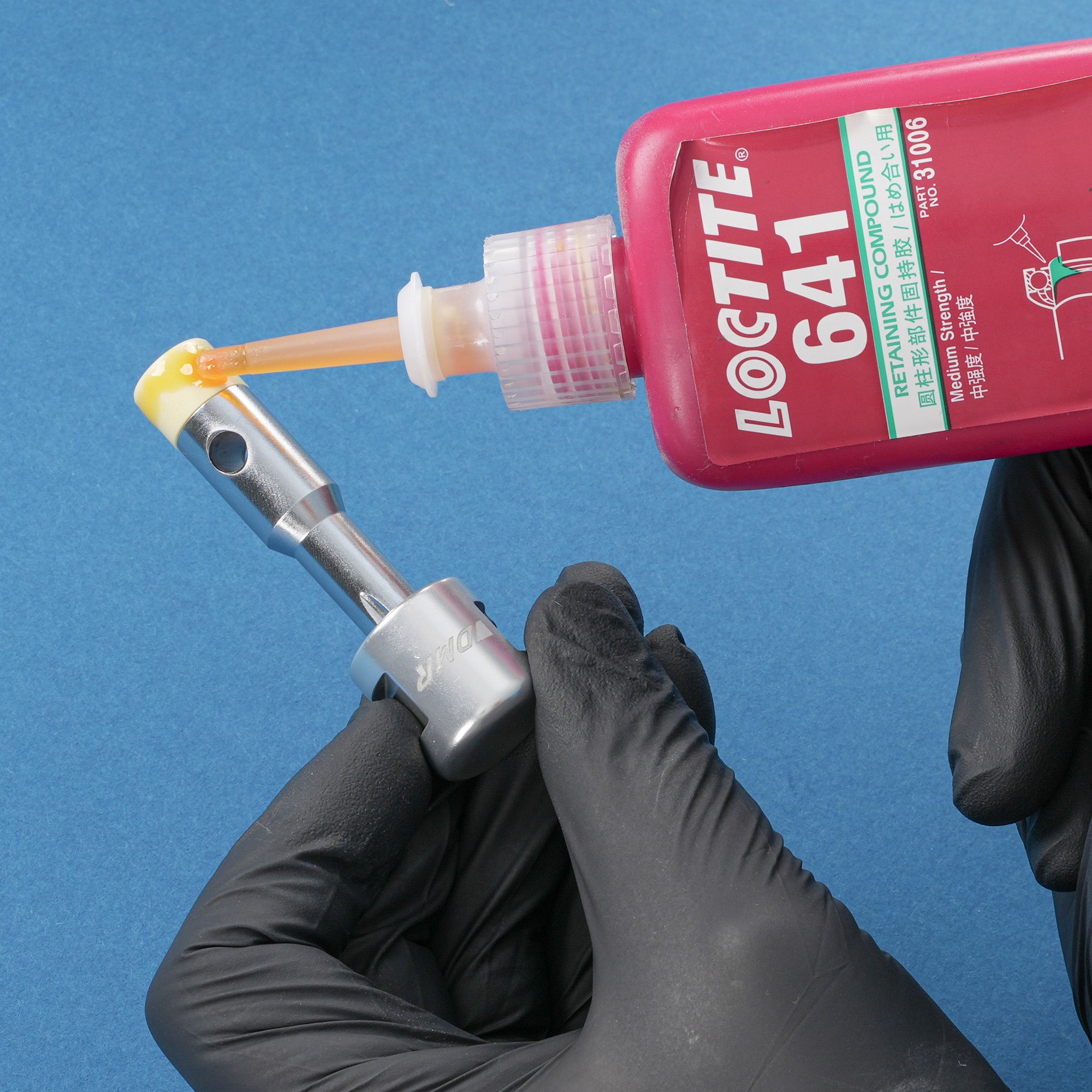 Loctite 641 being applied to silver dmr bikes bicycles vmax vault mag magnesium midi v12 v11 flat4 flat 4 four versa clip clipless pedals pedal service servicing tool on a blue background