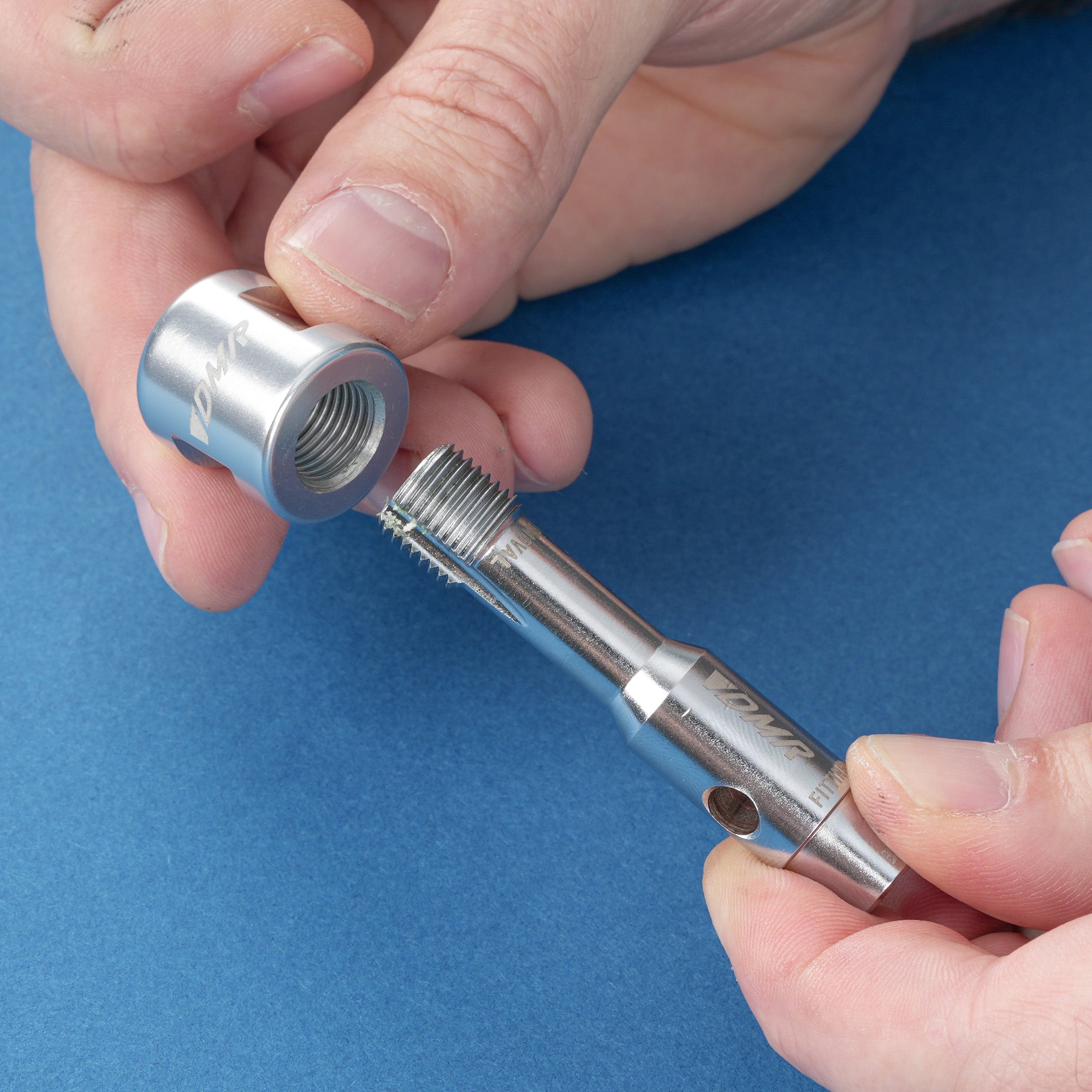 Hands holding the silver dmr bikes bicycles vmax vault mag magnesium midi v12 v11 flat4 flat 4 four versa clip clipless pedals pedal service servicing tool on a blue background