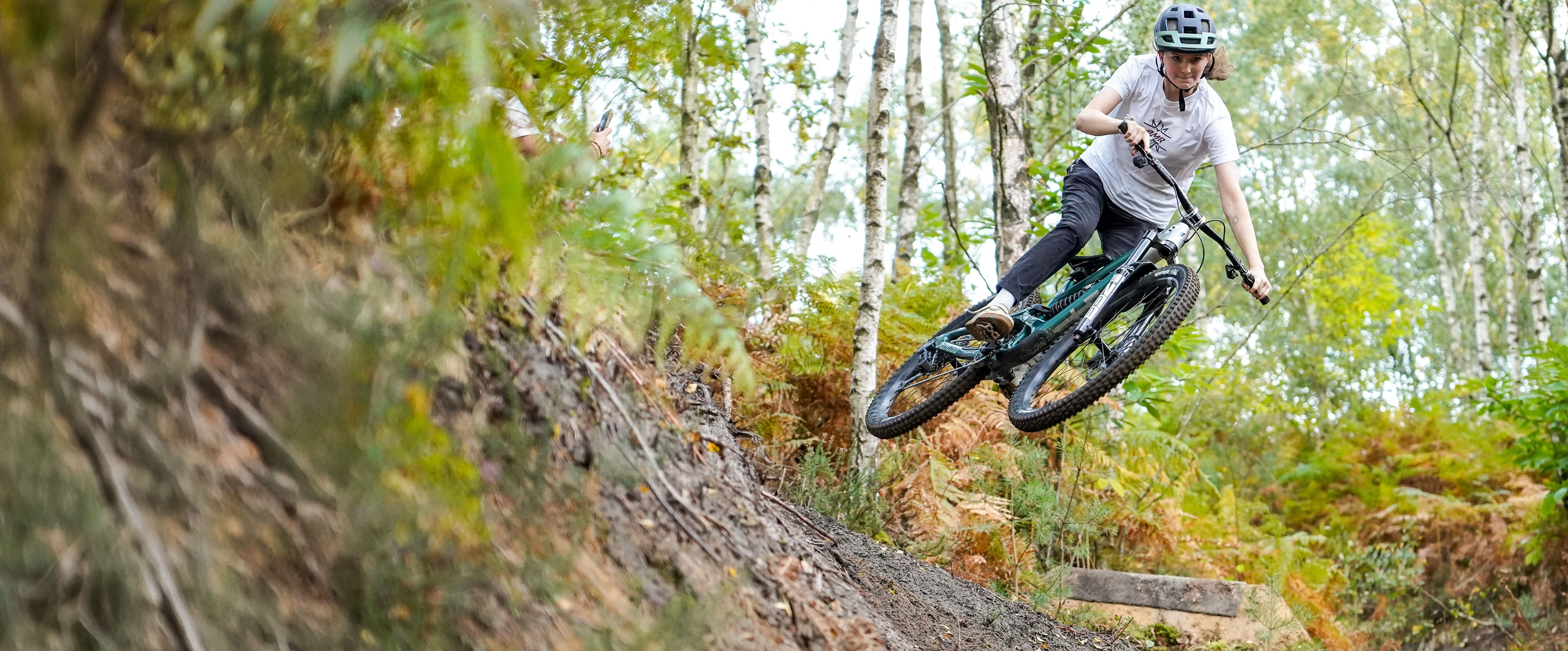 Person riding a mountain bike on a trail with trees in the background
