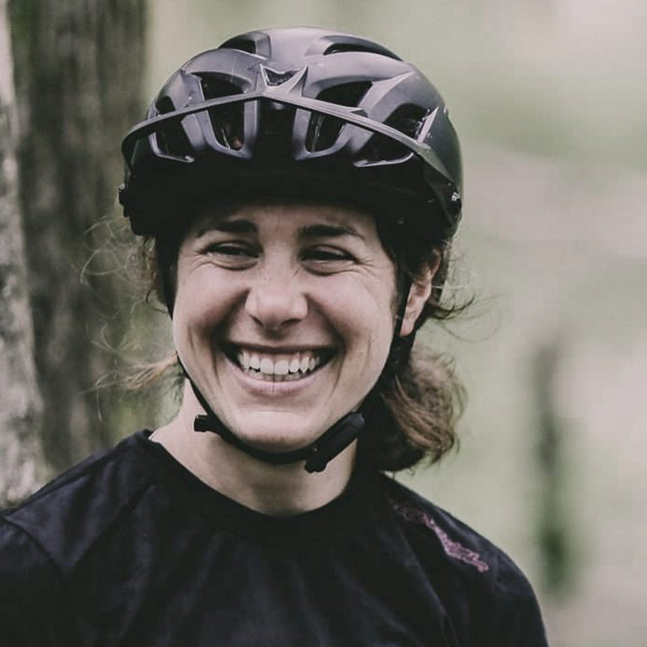 Person wearing a black helmet and black shirt in a forest setting