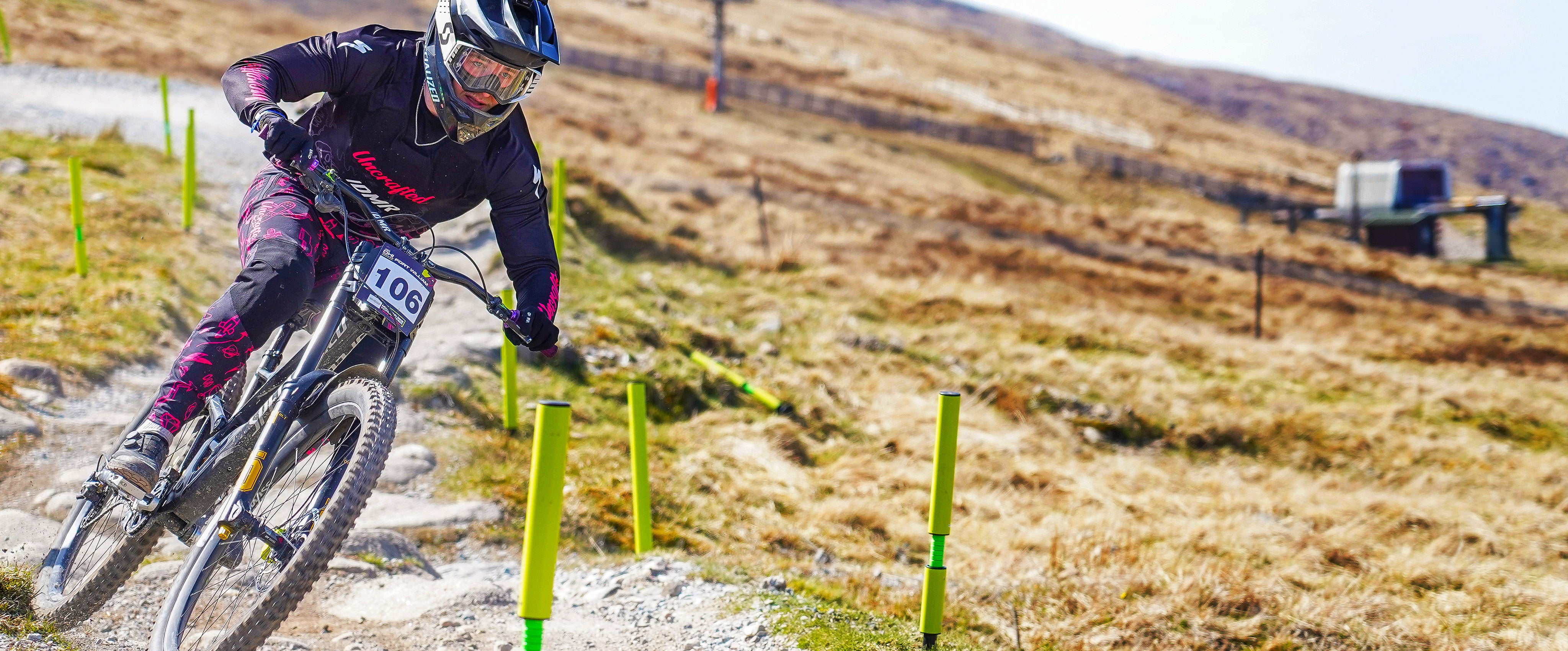 Person riding a mountain bike on a trail with yellow markers in a natural setting