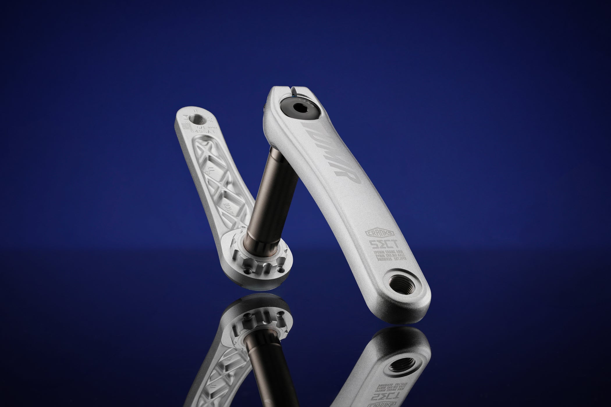 DMR Sect Cranks in Silver, on a reflective surface, with a gradient blue to black background.