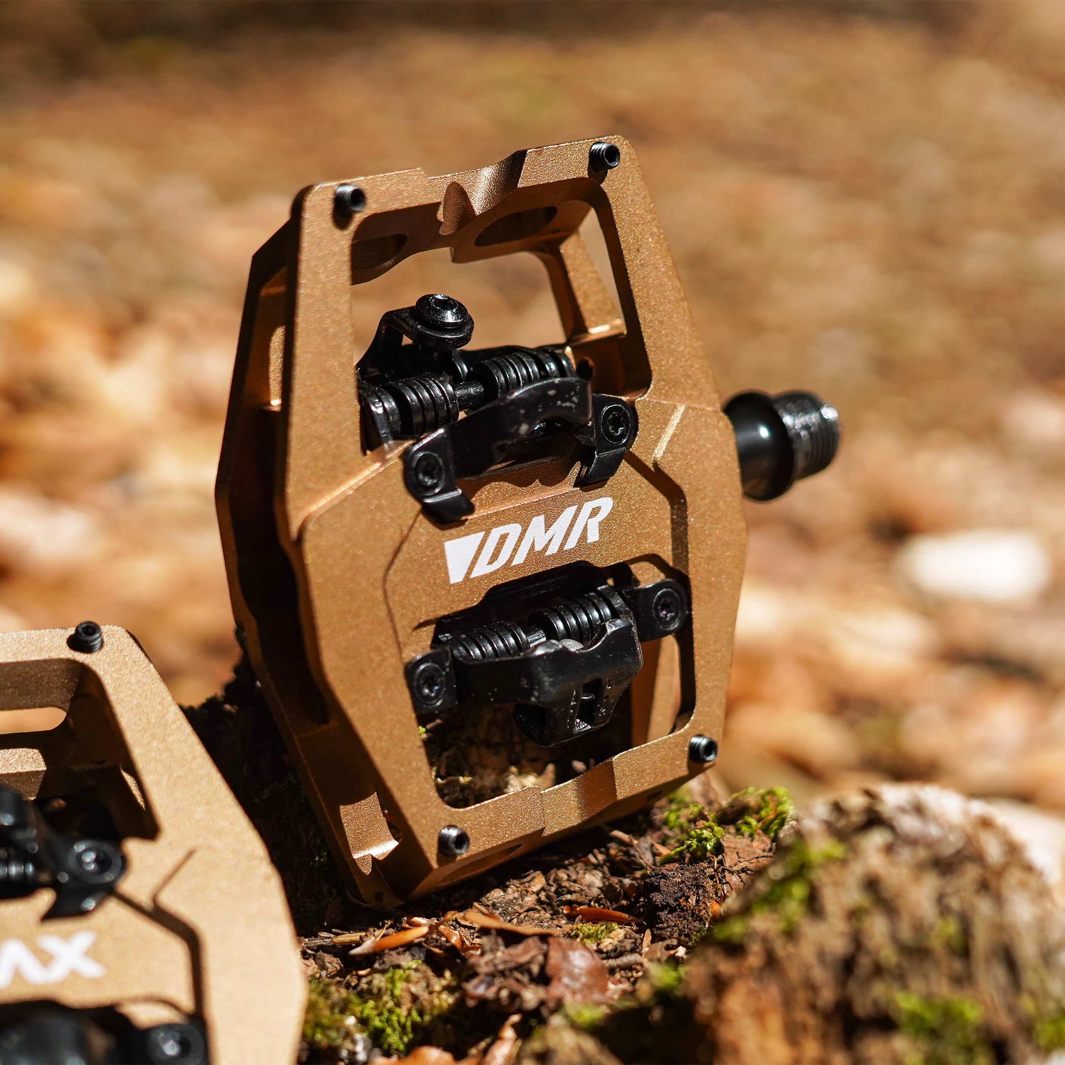 Close-up of the Light Bronze DMR VMAX clipless clip-in clip clipped SPD off-road mountain cycling bicycle bike pedalling pedal product, with an autumnal background composing of leaves other foliage.