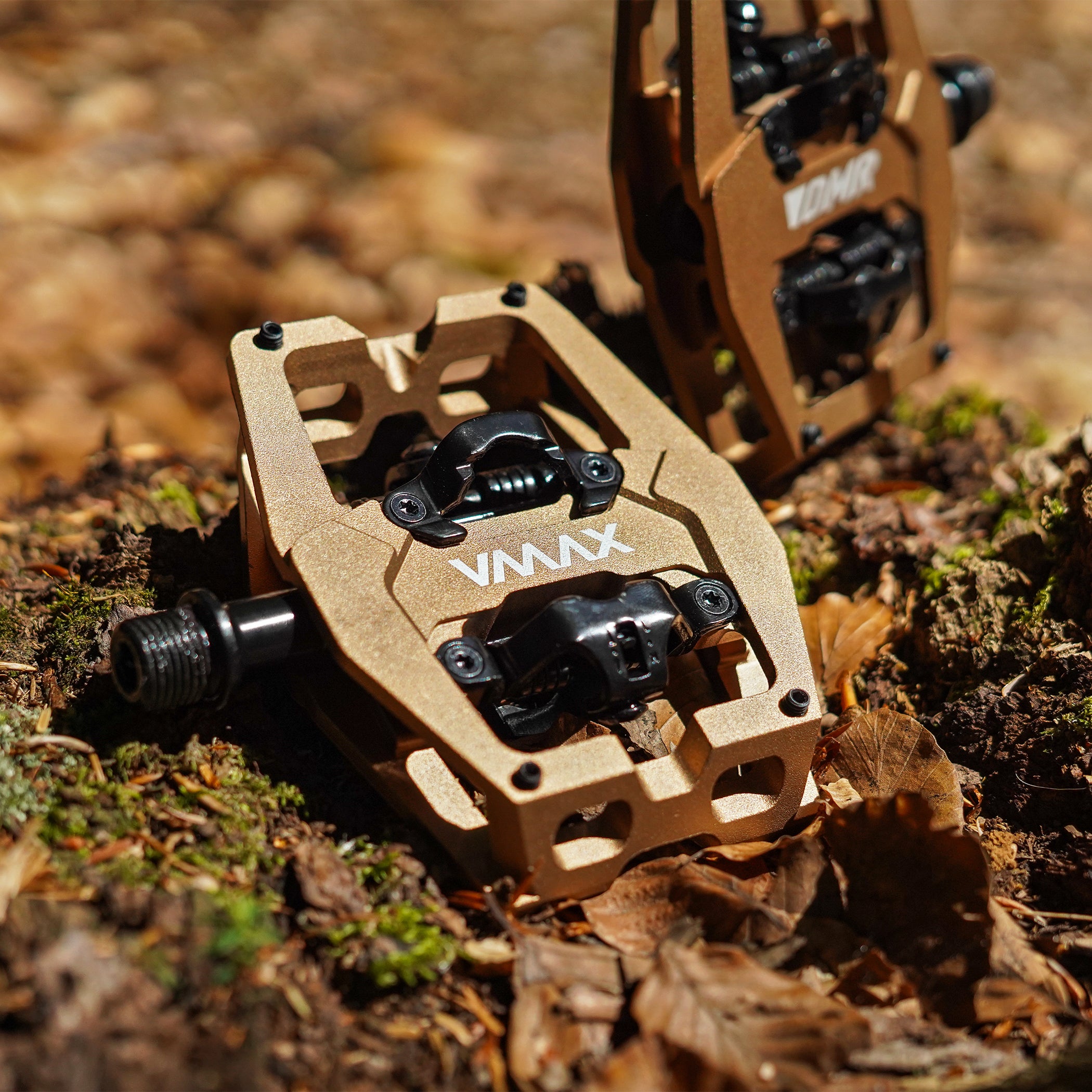 Close-up of the Light Bronze DMR VMAX clipless clip-in clip clipped SPD off-road mountain cycling bicycle bike pedalling pedal product, with an autumnal background composing of leaves other foliage.