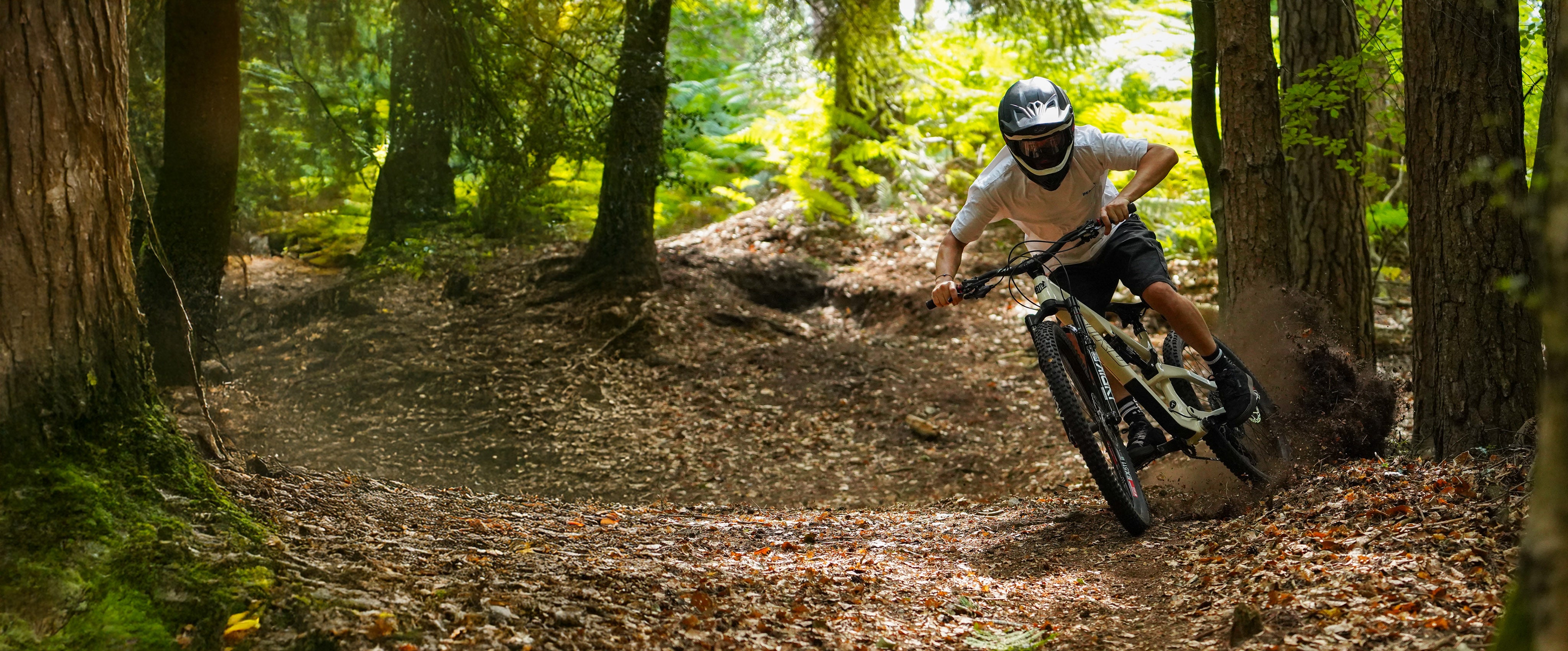 Person riding a mountain bike through a forest trail