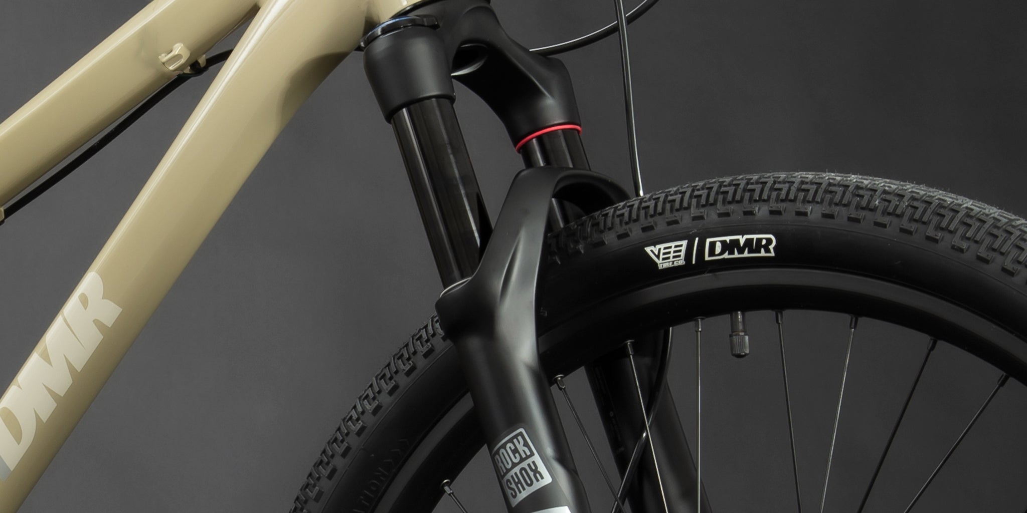 close-up of a dmr bikes rhythm team dirt jumper bike frame in sand brown, on a grey background